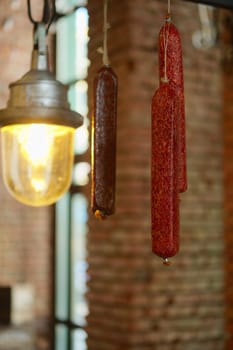 Smoked  sausagees hanging on a hook under the ceiling. Photo with shallow depth of field.