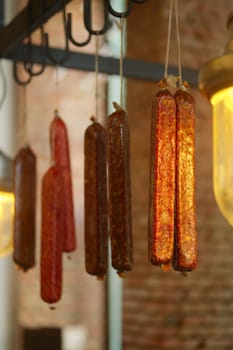 Smoked  sausagees hanging on a hook under the ceiling. Photo with shallow depth of field.