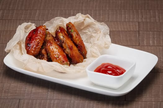 Closeup view of fried chicken wings with ketchup in wrapping paper