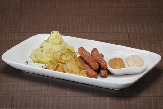 Homemade sausage with mashed potato and sauerkraut and mustard with horseradish.