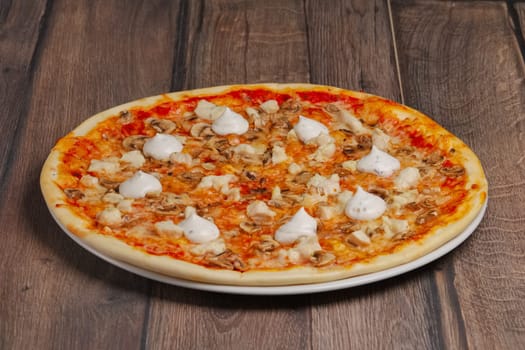 Angle side view of pizza with mushrooms and mayonnaise sause cutted on pieces.