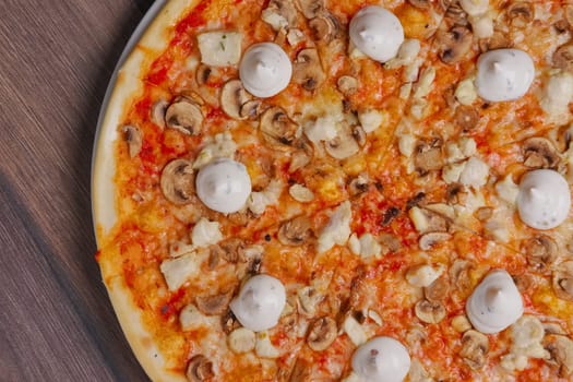 Top view of pizza with mushrooms and mayonnaise sauce cutted on pieces.