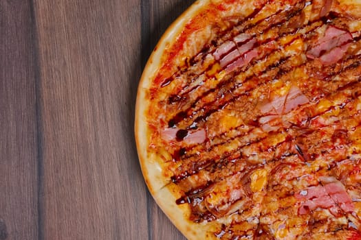 Top view of pizza with ham and balsamic sauce cutted on pieces.