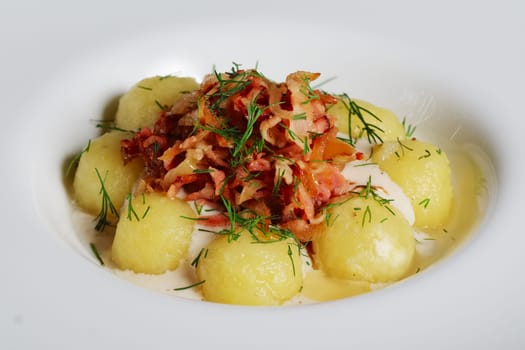 Close-up gnocchi, smoked bacon and cream sauce on wooden table.