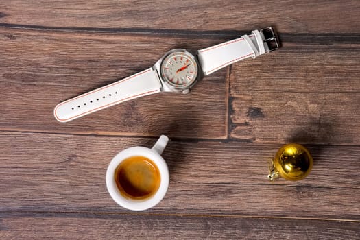 Top view of wrist watch, coffee and christmas tree toy on wooden table