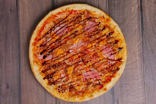 Top view of pizza with ham and balsamic sauce cutted on pieces.