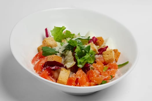 Plate with salmon, tomato and egg salad on white background