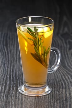 Transparent glass of rosemary, lemon and honey tea on wooden table