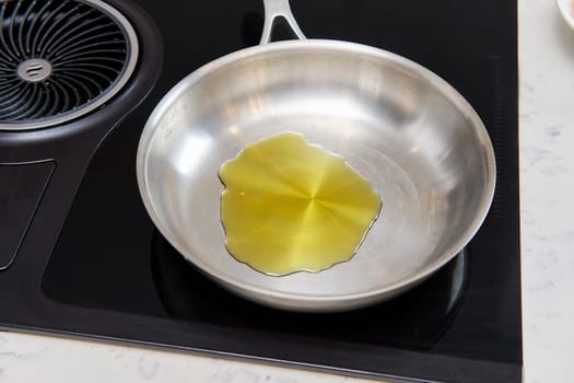 Metal frying pan with olive oil on the stove, view from above