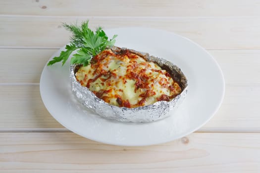 Meat baked in foil with vegetables and cheese on wooden table