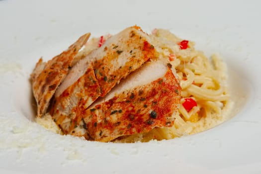 Closeup of plate with pasta, cheese and chicken fillet