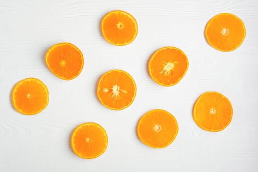 Top view of orange slices on white rustic wooden background, flat lay