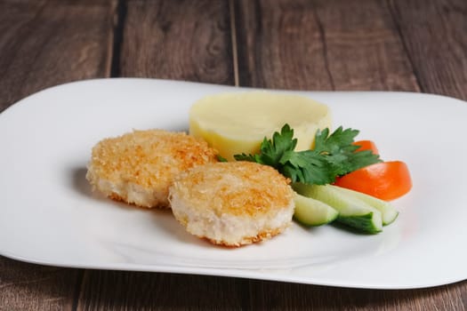 Plate with salmon cutlet with mashed potato and fresh cucumber and tomato