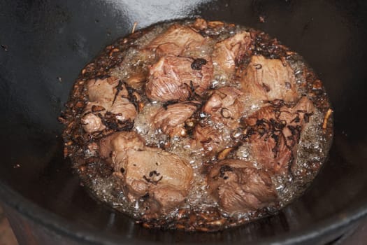 Meat and onions in cauldron. The making of pilaf, step by step.
