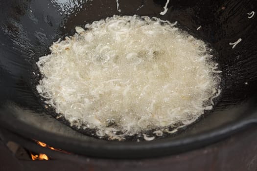 Frying onion in oil in cauldron. The making of pilaf, step by step.