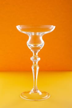 Empty glass for cocktail or dessert on orange background