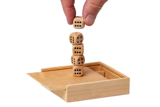 On an open wooden box a hand stacks playing cubes to form a tower. Isolated on white. Macro. Business concept. Mock up.