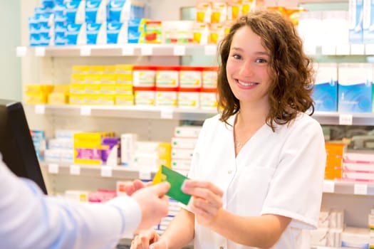 View of an Attractive pharmacist taking healt insurance card