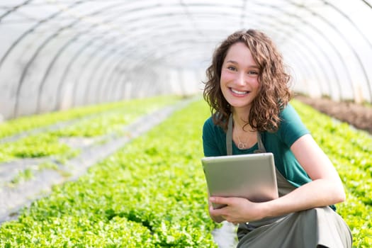 View of an attractive farmer in a greenhouse using tablet
