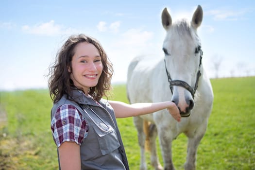 View of a young attractive veterinary in fields with horse