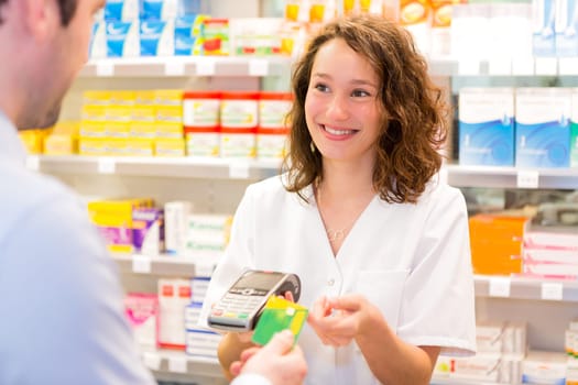 View of an Attractive pharmacist taking healt insurance card