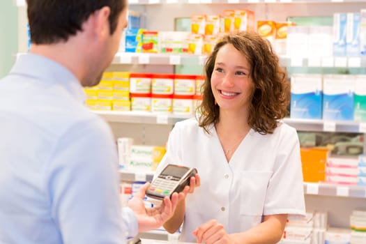 View of an Attractive pharmacist taking healt insurance card