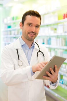 View of an Attractive pharmacist using tablet at work