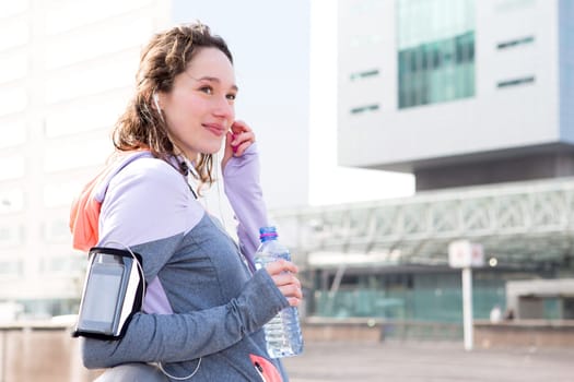 View of a Young attractive woman adjust her music player before running
