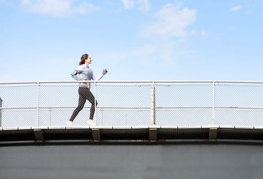View of a Young attractive woman running on a bridge