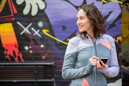 View of a Young attractive woman adjust her music player before running