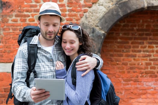 View of a Young couple of tourists using tablet to visit city