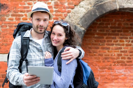 View of a Young couple of tourists using tablet to visit city