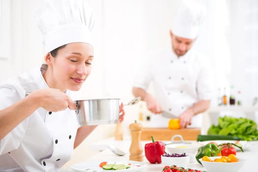 View of a Young attractive professional chef tasting sauce