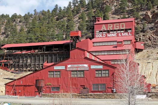 Idaho Springs, CO, USA - April 21, 2014: Large, red painted Argo gold mine and mill with a historical mining museum in front of a rising mountain. The Argo gold mine, mill and museum is a very popular tourist attraction in this small town.