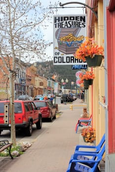 Idaho Springs, CO, USA - April 21, 2014: Picturesque and relaxing view of downtown Miner Street in a spring day. Colorful signs and seats decorate storefronts in the main shopping district of this town built around mining and tourism.
