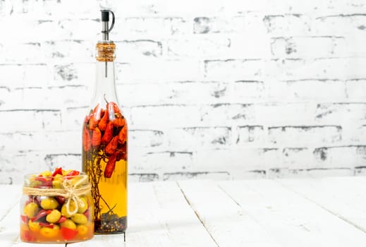 olives and hot pepper sauce in a bottle on the old white table