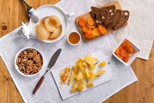 Overhead view of set of various appetizers for wine - cheese, walnuts, dried apricots, honey and canned pear