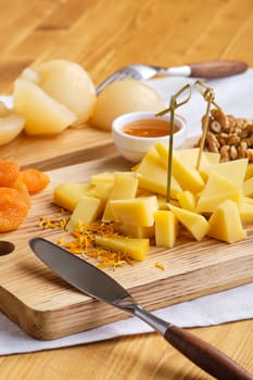 Close up view of set of various appetizers for wine - cheese, walnuts, dried apricots, honey and canned pear