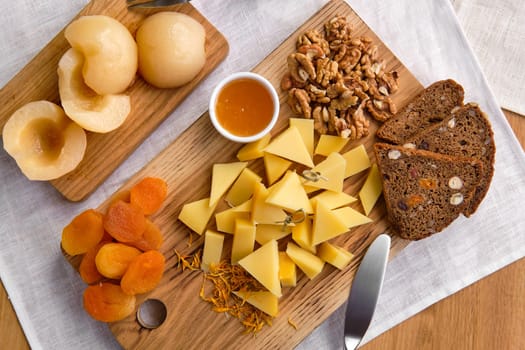Overhead view of set of various appetizers for wine - cheese, walnuts, dried apricots, honey and canned pear