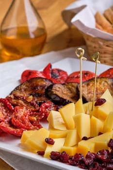 Close up view of  set of various appetizers for wine - cheese, sun-dried tomatoes, roasted eggplant, bell pepper, hardtack and dried cranberry