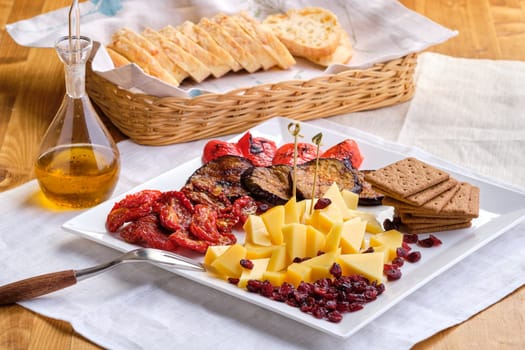 Set of various appetizers for wine - cheese, sun-dried tomatoes, roasted eggplant, bell pepper, hardtack and dried cranberry