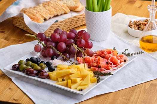 Set of various appetizers for wine - cheese, prosciutto, grape, olives, walnuts and celery