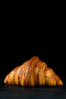 Fresh golden croissant on black table