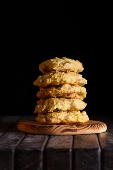 Low key photo of  stack of of ginger, lemon and apple biscuits on wooden table. Chocolate chip cookies on dark wooden background with copy space.