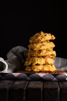 Low key photo of  stack of of ginger, lemon and apple biscuits on wooden table. Chocolate chip cookies on dark wooden background with copy space.