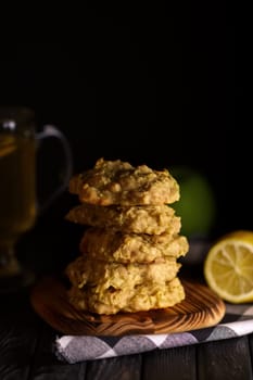 Low key photo of  stack of of ginger, lemon and apple biscuits on wooden table. Chocolate chip cookies on dark wooden background with copy space.