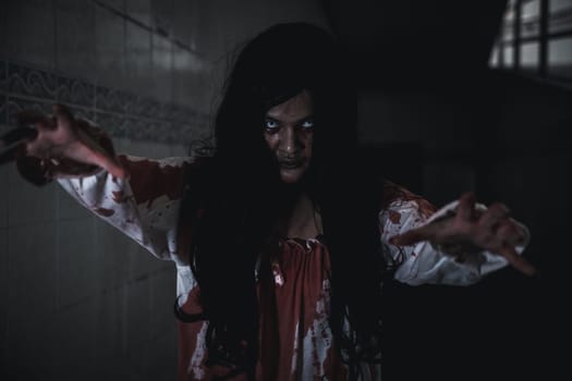 Scary zombies ghost walk. Asian female makeup zombie, woman ghost horror creepy scary have hair covering face with blood walking following camera at abandoned dark tone, Happy Halloween day
