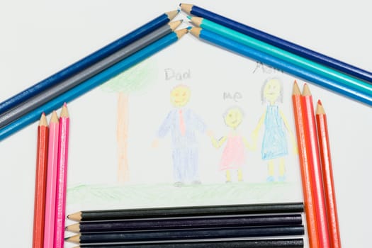 Multicolored pencils at a white paper with a child's family picture