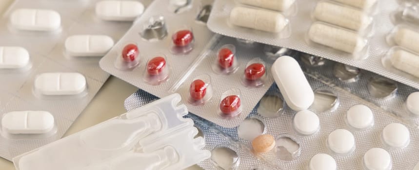 Mix of pills and capsules in a aluminum and plastic blisters with some missing pills already used on light beige close up. Preventive medicine and healthcare, taking dietary supplements and vitamins