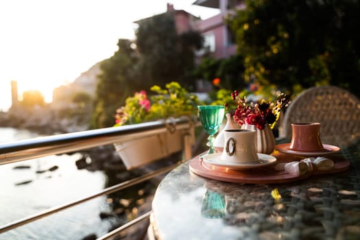 front view closeup of traditional Turkish coffee cups served outside with water flowers and delight dessert in romantic setup on glass table at sunset